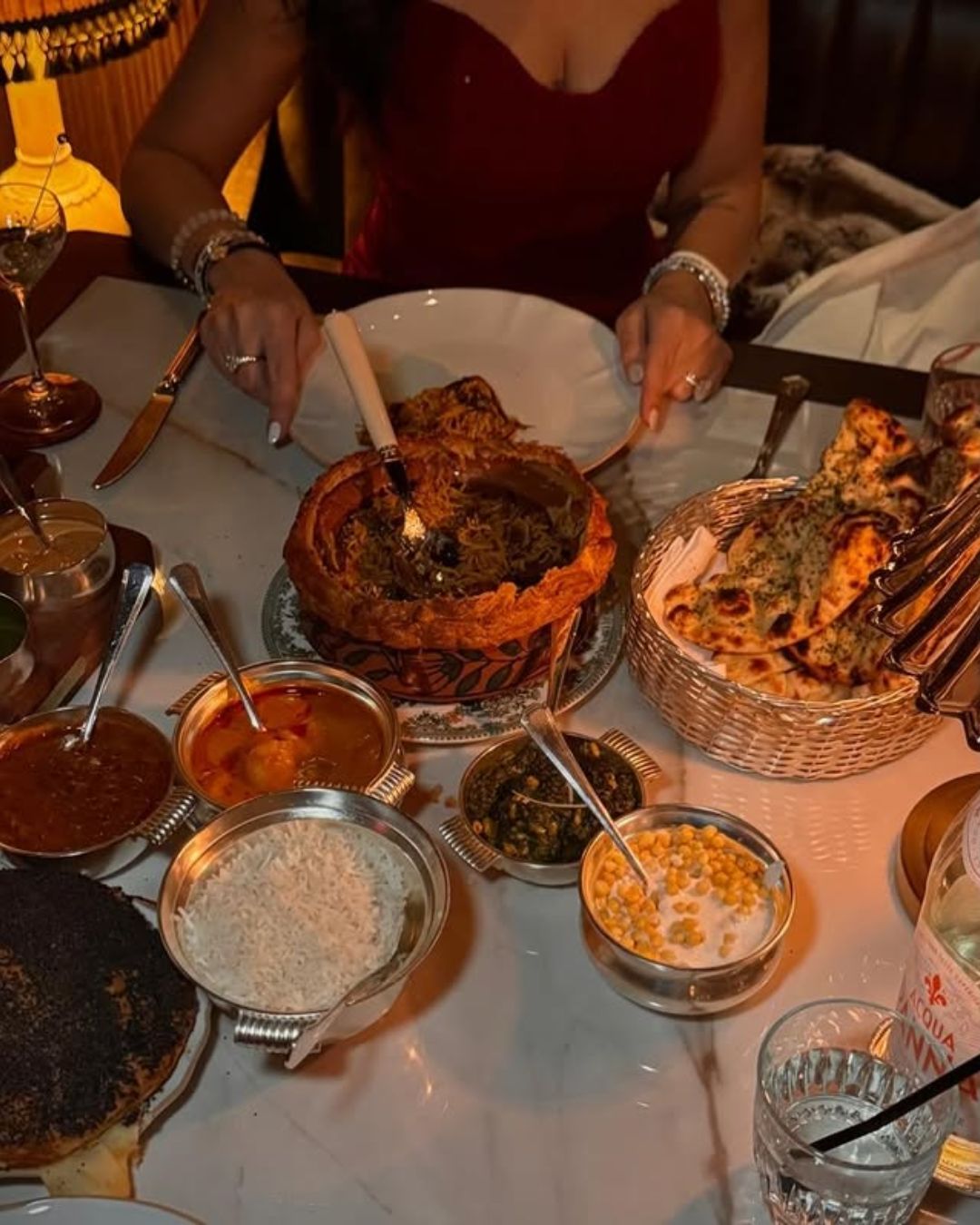 The sultry, highly sophisticated interior of Gymkhana at ARIA, featuring dark wood, leather booths, and an elevated Indian dining spread.