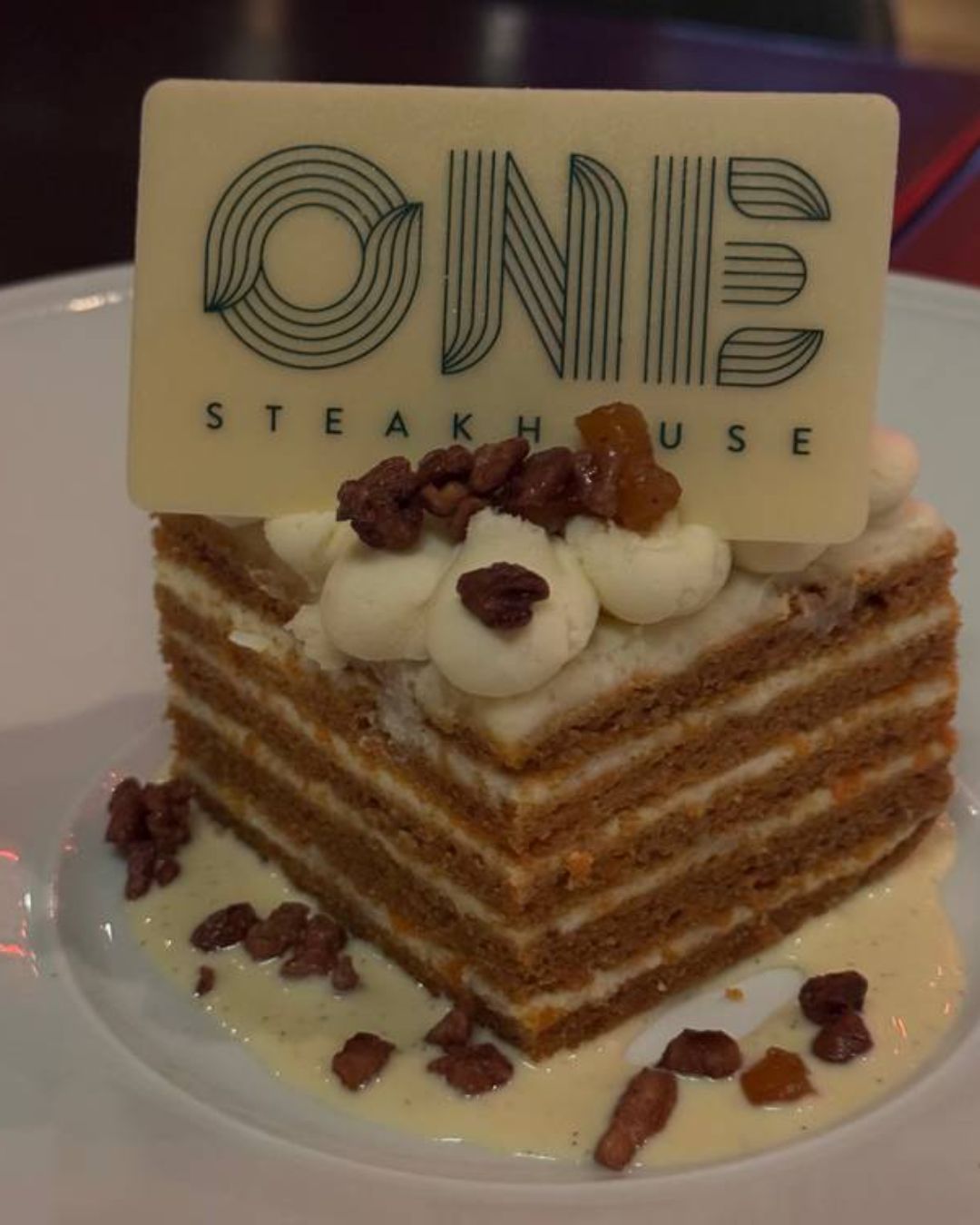 A moody, high-energy interior view of ONE Steakhouse, showing the mesmerizing 3,000-light LED chandelier from above.